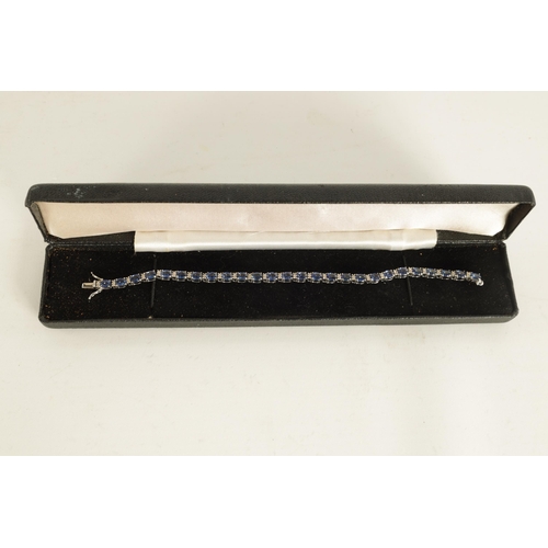 246 - A LADIES 18CT WHITE GOLD DIAMOND AND SAPPHIRE TENNIS BRACELET set with 26 oval-cut sapphires, each l... 