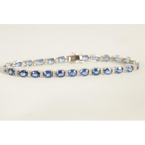 246 - A LADIES 18CT WHITE GOLD DIAMOND AND SAPPHIRE TENNIS BRACELET set with 26 oval-cut sapphires, each l... 