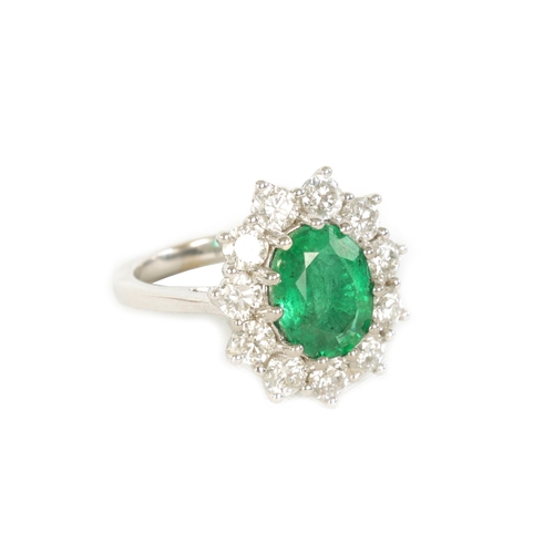 253 - A LARGE 18CT WHITE GOLD EMERALD AND DIAMOND RING set with a 3.31ct oval emerald surrounded by 11 bri... 