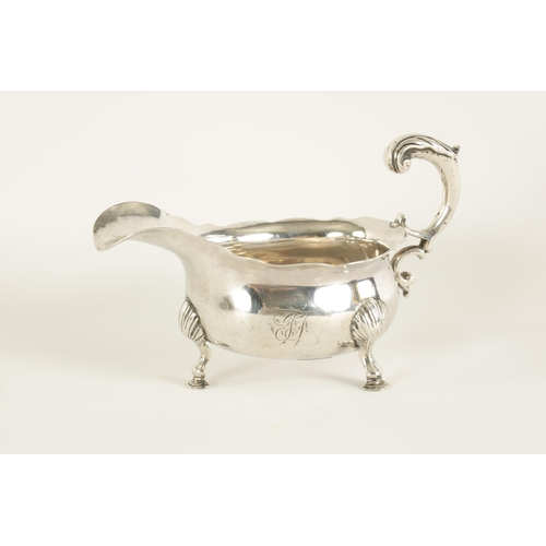 294 - A GEORGE II SILVER SAUCE BOAT of shallow oval form with acanthus capped leaf scroll handle, shell kn... 