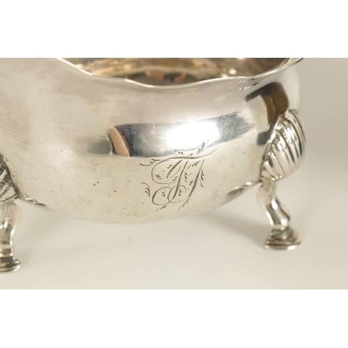 294 - A GEORGE II SILVER SAUCE BOAT of shallow oval form with acanthus capped leaf scroll handle, shell kn... 