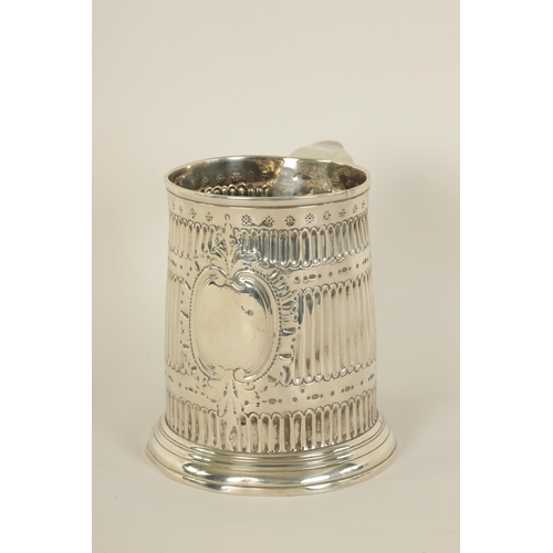 307 - AN EARLY GEORGIAN SILVER MUG the tapered body with fluted and punched decoration, shaped side handle... 