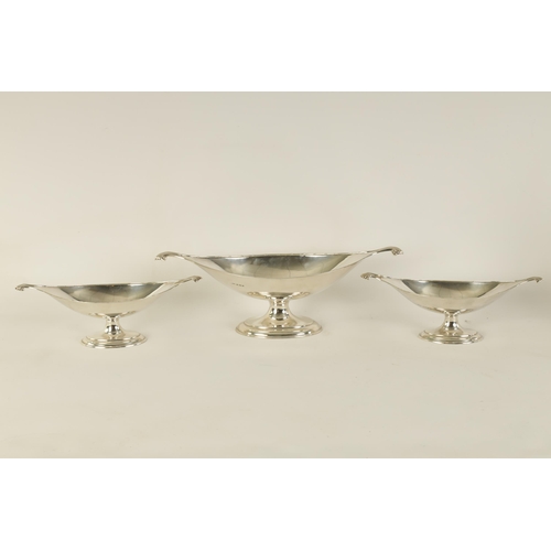 311 - A GRADUATED SET OF THREE EDWARD VII OVAL SILVER DESSERT DISHES with shell-shaped side handles standi... 