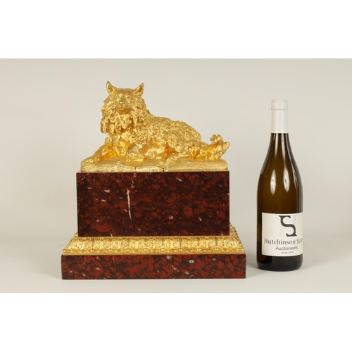 524 - A 19TH CENTURY GILT METAL AND ROUGE VEINED MARBLE SCULPTURE depicting a reclining dog, mounted on a ... 