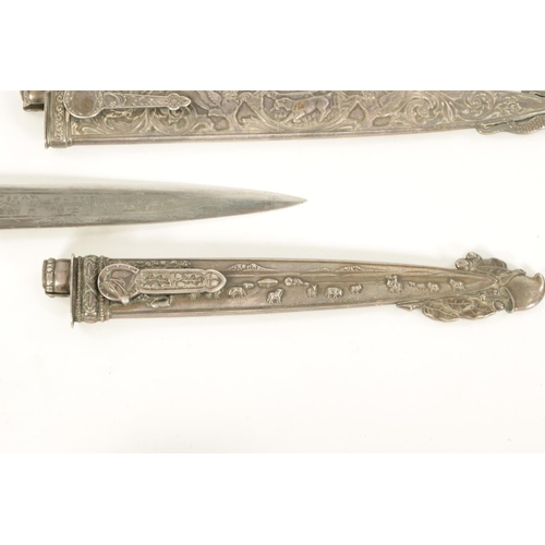 639 - TWO ARGENTINIAN SILVER GAUCHO KNIVES the larger with relief decoration depicting dogs within a carto... 