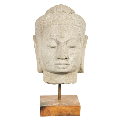 139 - A LARGE CARVED STONE TIBETAN BUDDHIST HEAD mounted on later oak stand (69cm high)