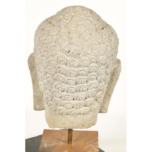 139 - A LARGE CARVED STONE TIBETAN BUDDHIST HEAD mounted on later oak stand (69cm high)