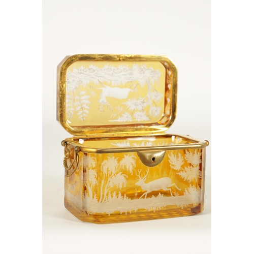 14 - A 19TH CENTURY BOHEMIAN AMBER GLASS OVERLAY CASKET with etched decoration depicting Stags amongst tr... 