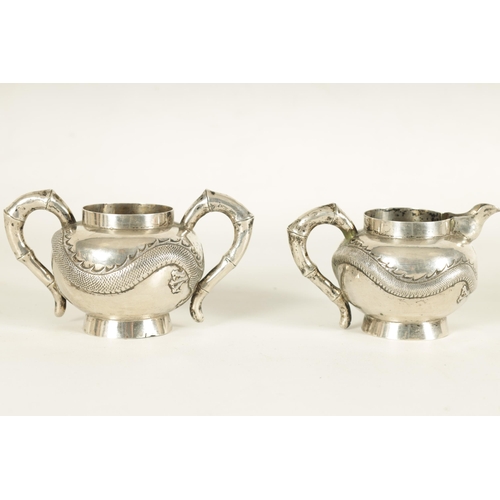 146 - A 19TH CENTURY CHINESE SILVER CREAM JUG AND SUGAR BOWL with bamboo handles and embossed swirling dra... 