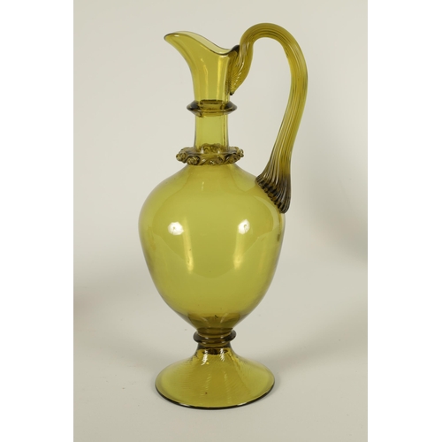 19 - A LATE 19TH CENTURY WHITEFRIARS STYLE GREEN GLASS EWER with slender neck and bulbous body, shaped ha... 