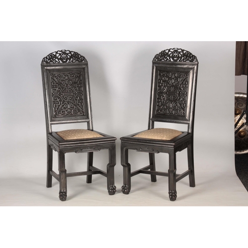 202 - A PAIR OF CHINESE HARDWOOD CHAIRS with carved pierced top rails above carved panelled backs and pad ... 