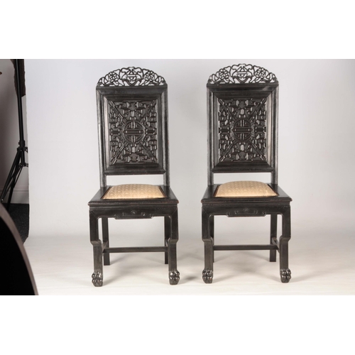 202 - A PAIR OF CHINESE HARDWOOD CHAIRS with carved pierced top rails above carved panelled backs and pad ... 