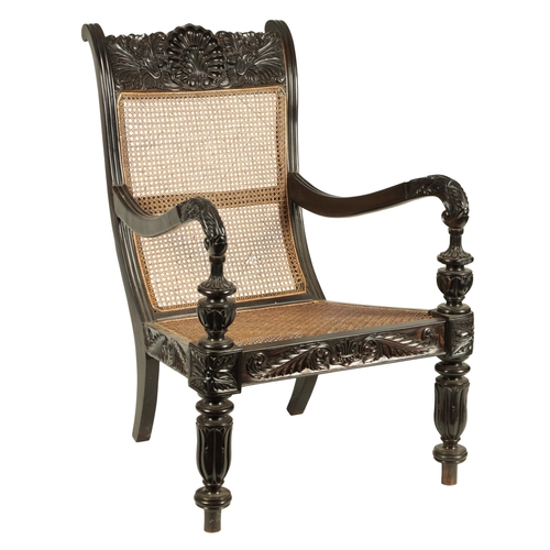 227 - AN IMPRESSIVE LATE REGENCY ANGLO INDIAN CARVED EBONY BERGERE OPEN ARMCHAIR OF GENEROUS SIZE with mou... 