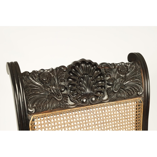 227 - AN IMPRESSIVE LATE REGENCY ANGLO INDIAN CARVED EBONY BERGERE OPEN ARMCHAIR OF GENEROUS SIZE with mou... 