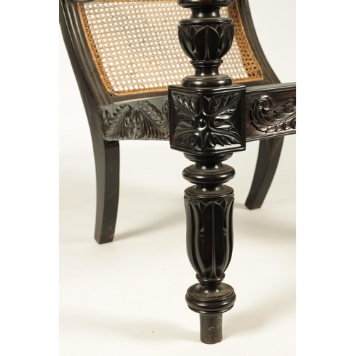 227 - AN IMPRESSIVE LATE REGENCY ANGLO INDIAN CARVED EBONY BERGERE OPEN ARMCHAIR OF GENEROUS SIZE with mou... 