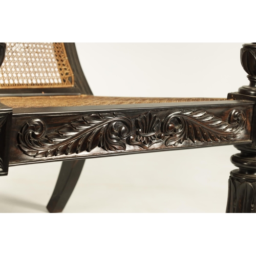 227 - AN IMPRESSIVE LATE REGENCY ANGLO INDIAN CARVED EBONY BERGERE OPEN ARMCHAIR OF GENEROUS SIZE with mou... 