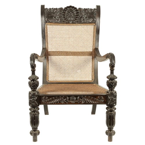 227 - AN IMPRESSIVE LATE REGENCY ANGLO INDIAN CARVED EBONY BERGERE OPEN ARMCHAIR OF GENEROUS SIZE with mou... 