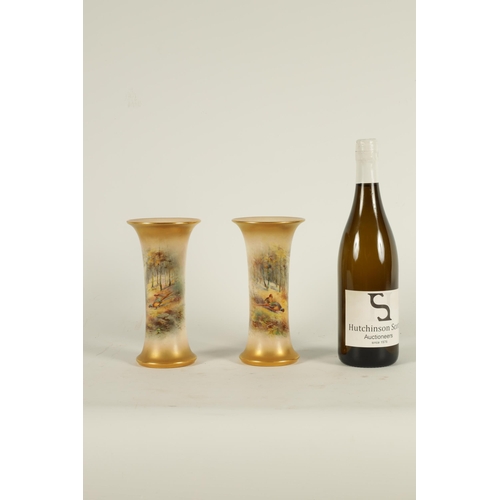 40 - JAMES STINTON. A PAIR OF ROYAL WORCESTER GILT EDGED FLARED CYLINDRICAL CABINET VASES painted with un... 