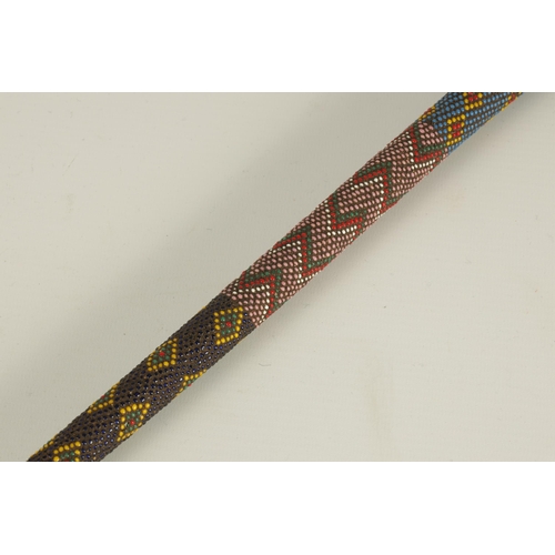 466 - A LATE 19TH CENTURY ZULU COLOURED BEADWORK WALKING CANE decorated multi geometric panels. (65cm over... 