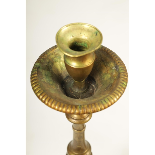 501 - A SET OF FOUR 18TH CENTURY CONTINENTAL LARGE BRASS CANDLESTICKS with cast leaf scrolled tripod bases... 