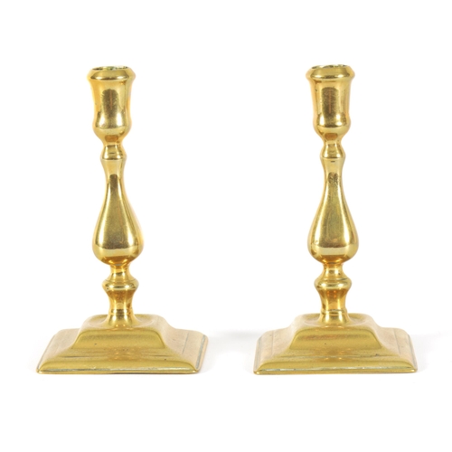 506 - A PAIR OF MID 18TH CENTURY CAST BRASS CANDLESTICKS the square baluster stems with tulips sconces on ... 