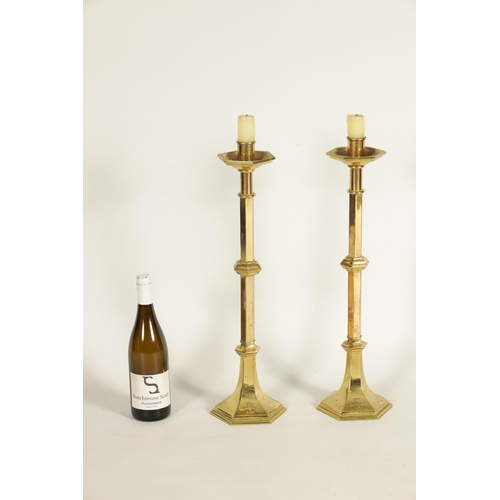 532 - A PAIR OF ARTS AND CRAFTS STYLE GOTHIC CAST BRASS CANDLESTICKS with knopped faceted stems and flared... 