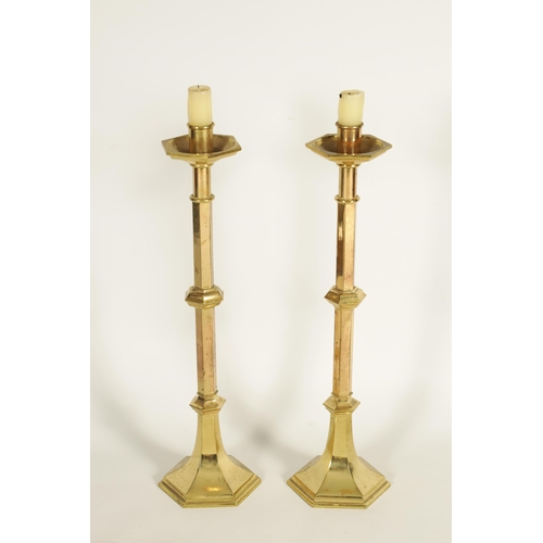 532 - A PAIR OF ARTS AND CRAFTS STYLE GOTHIC CAST BRASS CANDLESTICKS with knopped faceted stems and flared... 