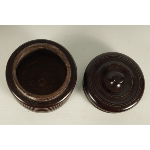 551 - A 19TH CENTURY TREENWARE LIGNUM VITAE CIRCULAR BOX AND COVER of ribbed form with ringed dished top a... 