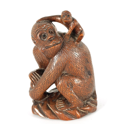 575 - A 19TH CENTURY CARVED HARDWOOD SCULPTURE OF A MONKEY modelled seated clutching a fruit and with infa... 