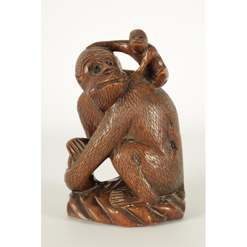 575 - A 19TH CENTURY CARVED HARDWOOD SCULPTURE OF A MONKEY modelled seated clutching a fruit and with infa... 