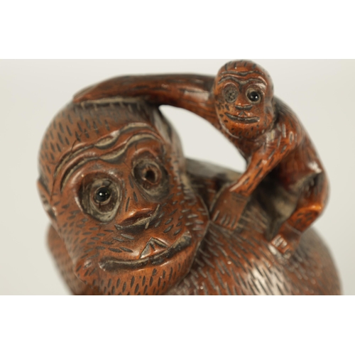 575 - A 19TH CENTURY CARVED HARDWOOD SCULPTURE OF A MONKEY modelled seated clutching a fruit and with infa... 