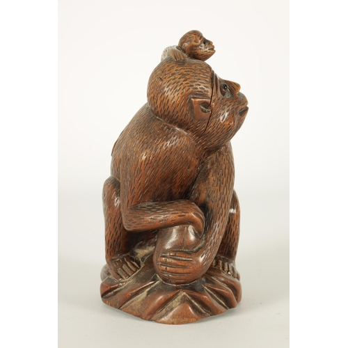 575 - A 19TH CENTURY CARVED HARDWOOD SCULPTURE OF A MONKEY modelled seated clutching a fruit and with infa... 