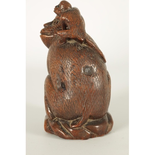 575 - A 19TH CENTURY CARVED HARDWOOD SCULPTURE OF A MONKEY modelled seated clutching a fruit and with infa... 