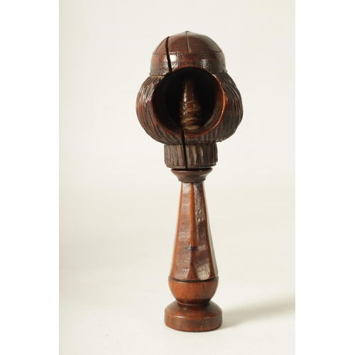 595 - AN 18TH CENTURY TREEN YEW WOOD NUTCRACKER modelled as a head wearing a hat on a faceted handle with ... 