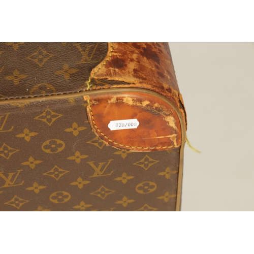 634 - A VINTAGE LOUIS VUITTON SUITCASE with a monogram covering and tan leather straps (78cm wide 53cm dee... 