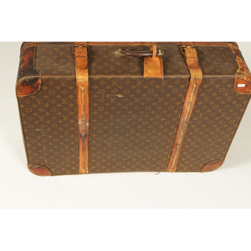 634 - A VINTAGE LOUIS VUITTON SUITCASE with a monogram covering and tan leather straps (78cm wide 53cm dee... 