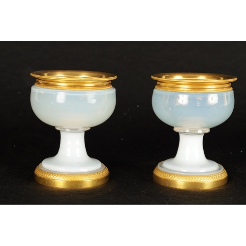 644 - A PAIR OF EARLY 19TH CENTURY FRENCH ORMOLU MOUNTED WHITE OPALINE GLASS CUPS of squat bulbous form ra... 