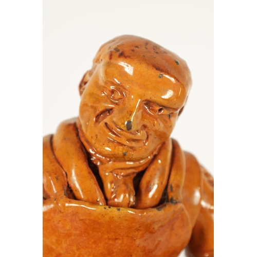 68 - A MID 19TH CENTURY PILL POTTERY WELSH REDWARE GLAZED EARTHENWARE FIGURE modelled as a seated cobbler... 