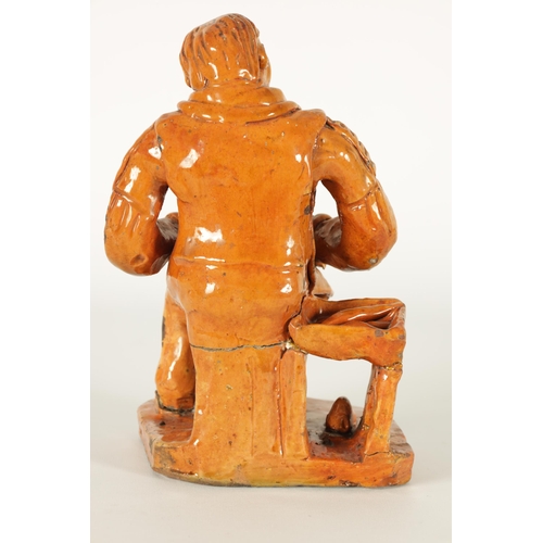 68 - A MID 19TH CENTURY PILL POTTERY WELSH REDWARE GLAZED EARTHENWARE FIGURE modelled as a seated cobbler... 