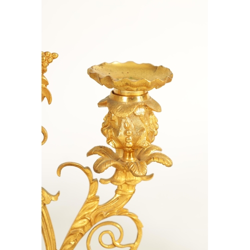 683 - A PAIR OF REGENCY BRONZE AND ORMOLU TWO BRANCH CANDELABRA the floral sconces on scrolling acanthus b... 