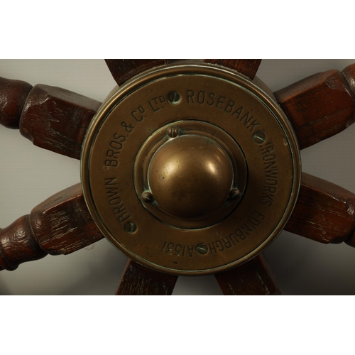 702 - A LATE 19TH CENTURY BRASS MOUNTED OAK SHIP'S WHEEL BY BROWN BOTHERS, EDINBURGH having eight turned s... 