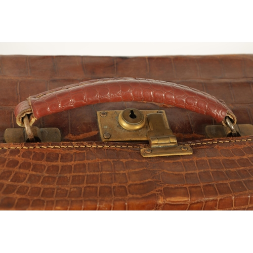 709 - AN EARLY 20TH CENTURY CROCODILE SKIN SUITCASE with gilt brass lock and old shipping labels (40cm wid... 