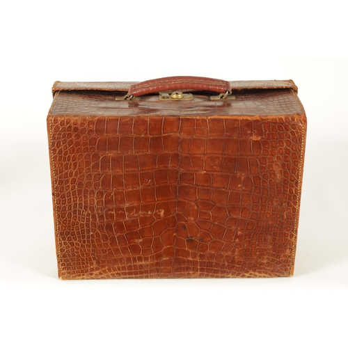 709 - AN EARLY 20TH CENTURY CROCODILE SKIN SUITCASE with gilt brass lock and old shipping labels (40cm wid... 