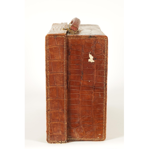 709 - AN EARLY 20TH CENTURY CROCODILE SKIN SUITCASE with gilt brass lock and old shipping labels (40cm wid... 