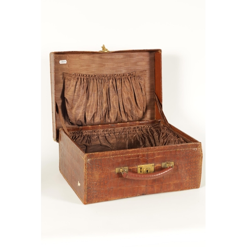 709 - AN EARLY 20TH CENTURY CROCODILE SKIN SUITCASE with gilt brass lock and old shipping labels (40cm wid... 