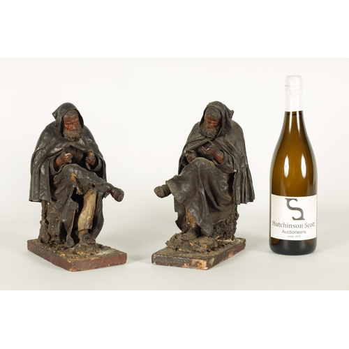 721 - A PAIR OF EARLY PRESSED LEATHER CREICHE SEATED FIGURES both seated with hooded cloaks (26cm high)