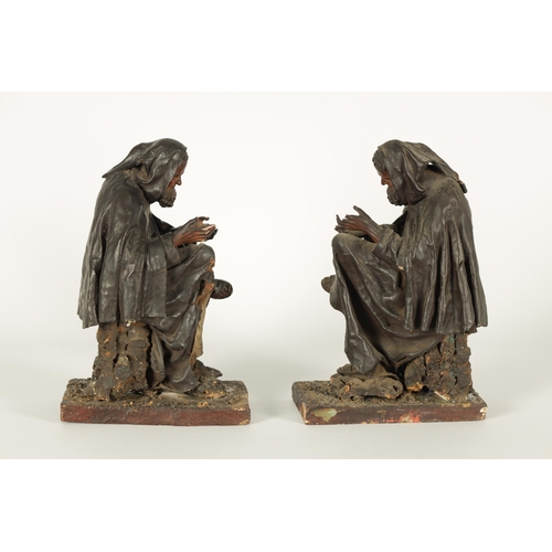 721 - A PAIR OF EARLY PRESSED LEATHER CREICHE SEATED FIGURES both seated with hooded cloaks (26cm high)