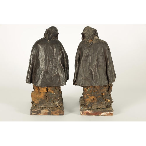 721 - A PAIR OF EARLY PRESSED LEATHER CREICHE SEATED FIGURES both seated with hooded cloaks (26cm high)