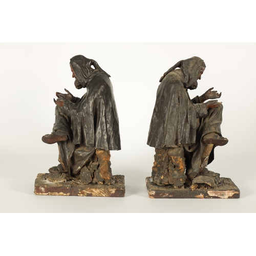 721 - A PAIR OF EARLY PRESSED LEATHER CREICHE SEATED FIGURES both seated with hooded cloaks (26cm high)