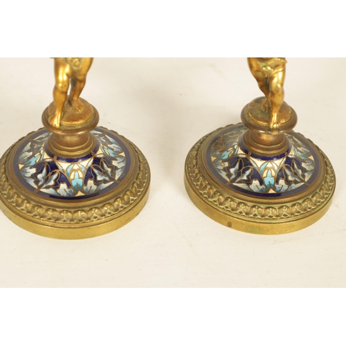 729 - A PAIR OF 19TH CENTURY FRENCH FIGURAL GILT BRONZE AND CHAMPLEVE ENAMEL CANDLESTICKS modelled as two ... 